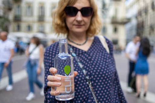 Donna fra i passanti tiene la bottiglia CLIK SODA piena d'acqua