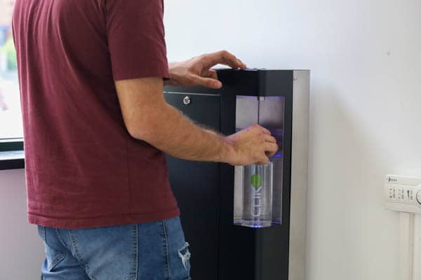 Una persona dell'ufficio Bewee riempia la bottiglia con acqua da un dispenser Clik Soda 